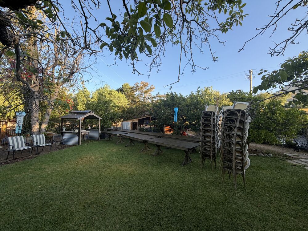 Stacked farm tables and cross-back chairs available for rent
